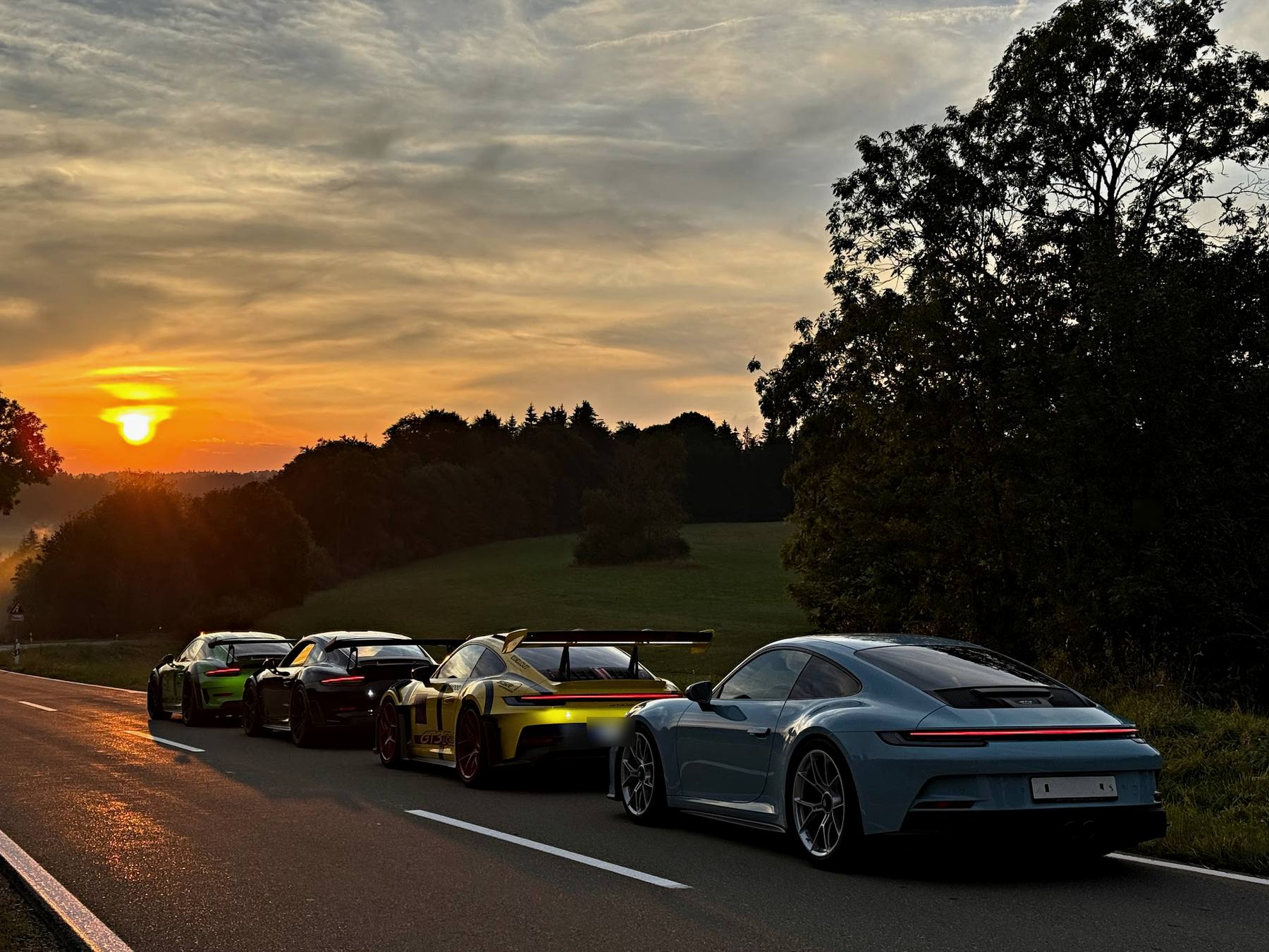 Porsche-Modelle bei Sonnenuntergang auf der Landstraße